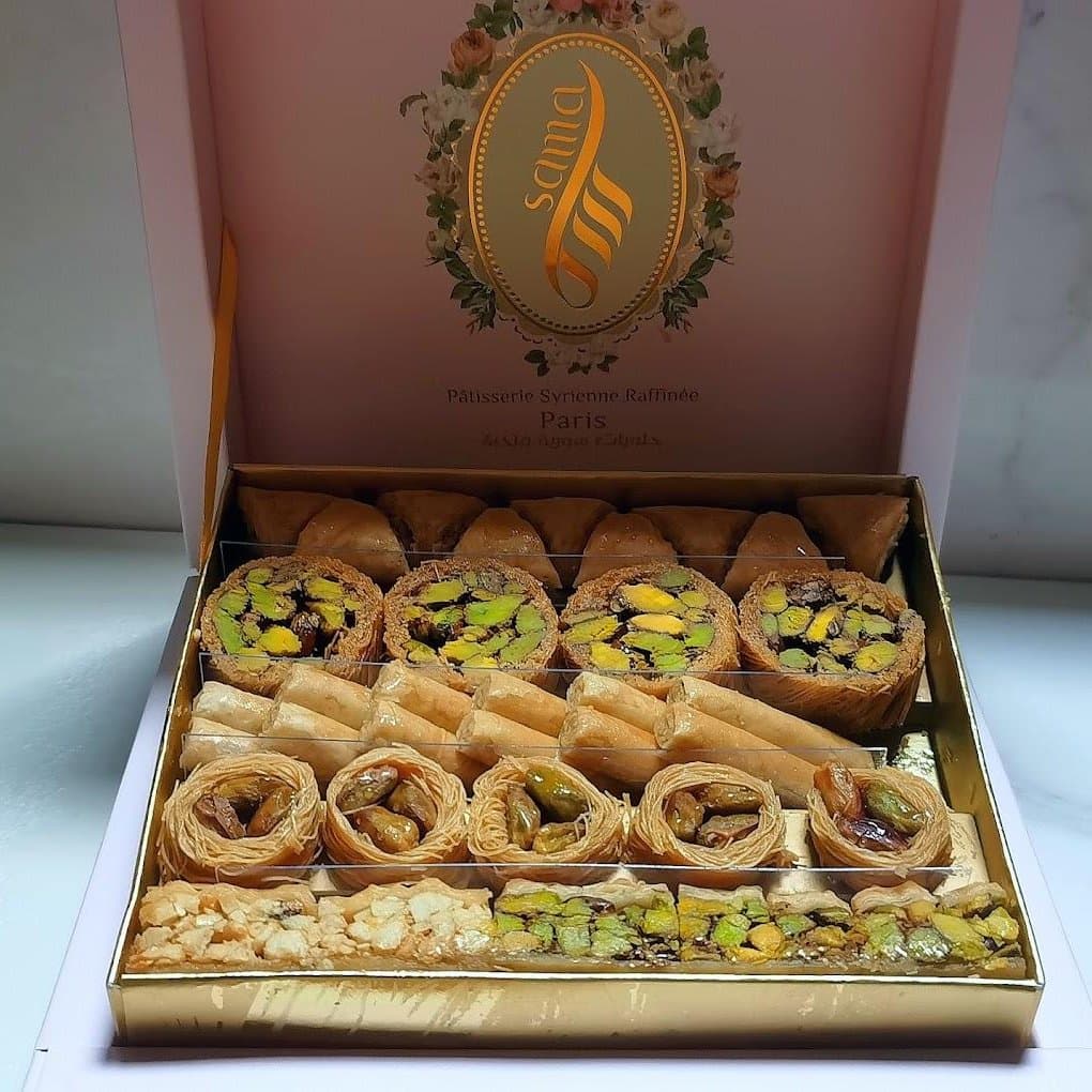 Coffret Sama ouvert sur un assortiment de baklawa à la pistache : triangles, rouleaux, nids et barres